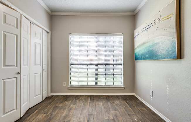 an empty room with a window and a painting on the wall