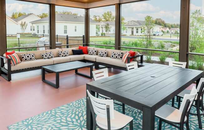 a screened patio with a couch table and chairs and large windows cottage at Anthem Apartments and Cottages in Huntsville, Alabama