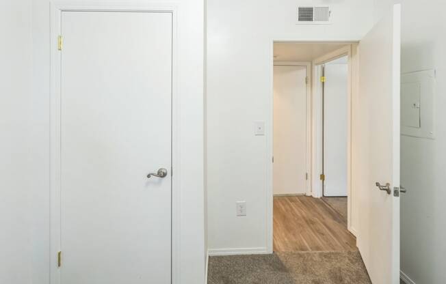 a bedroom with white walls and a door to a hallway