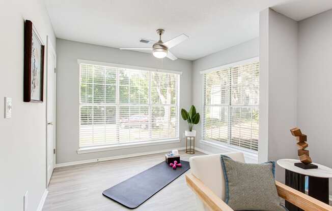 an empty living room with a yoga mat and a ceiling fan at Parc at 1875, College Park