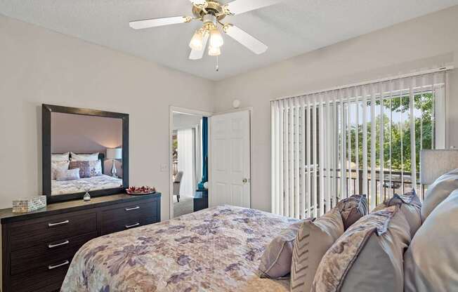 A bedroom with a ceiling fan and sliding glass patio door.