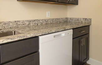 A kitchen with dark brown cabinets and a white dishwasher.