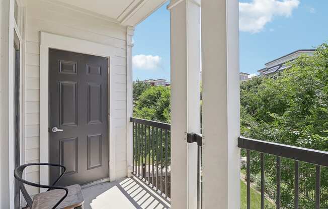 a balcony with a black door and a table and a chair