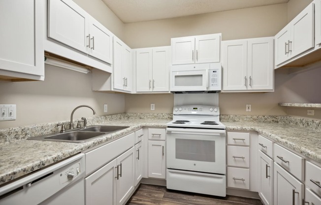 a kitchen with white cabinets and white appliances and granite counter tops