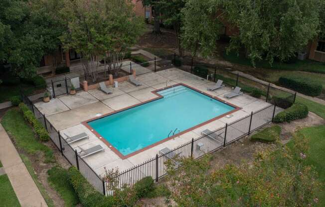 a pool with a fence around it in a yard with trees