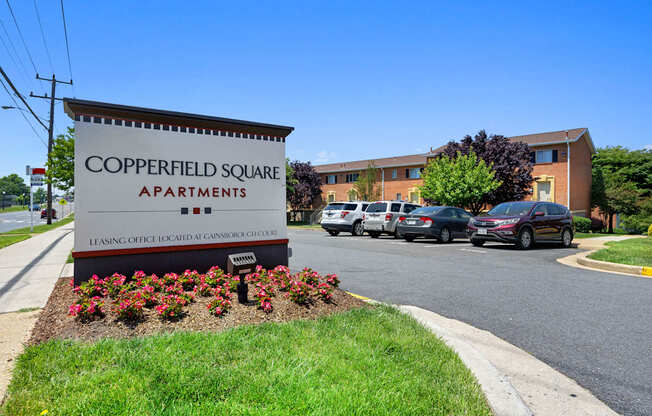 a sign for copperfield square apartments in front of a parking lot