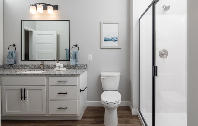 A white toilet sits in a bathroom next to a sink and mirror.