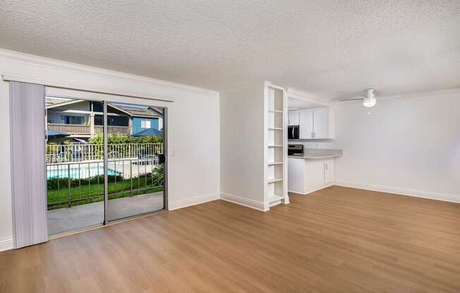 A spacious living room with a sliding glass door leading to a balcony.