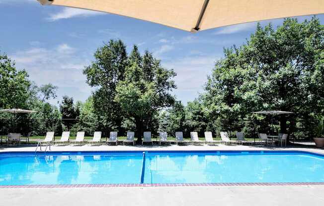 A large swimming pool surrounded by trees and lounge chairs. at Tranquility Pointe, Omaha, NE