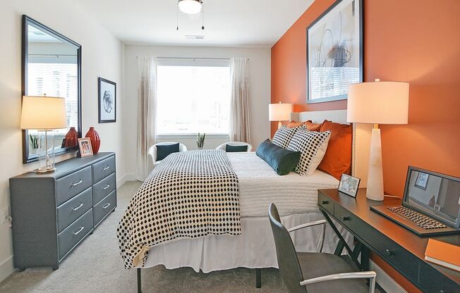 a bedroom with a bed and a desk with a laptop