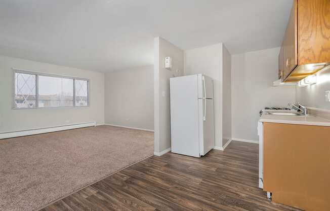 kitchen with wood cabinets and white fridge and attached living room