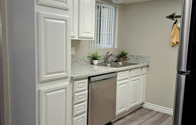 A kitchen with white cabinets and a stainless steel refrigerator.