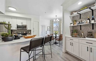 a kitchen with white cabinets and a white counter top with three stools in front of it