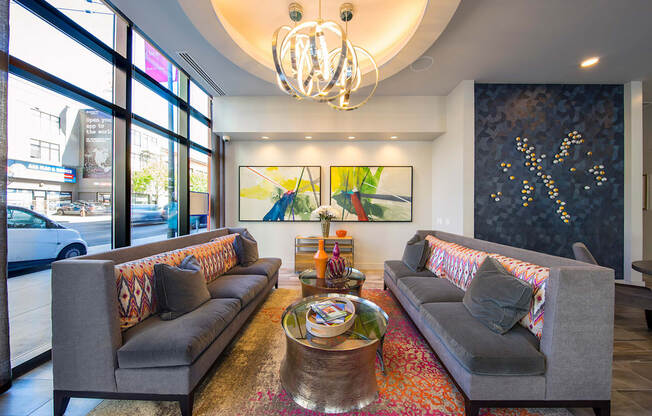 A living room with two grey couches, a coffee table, and a chandelier.