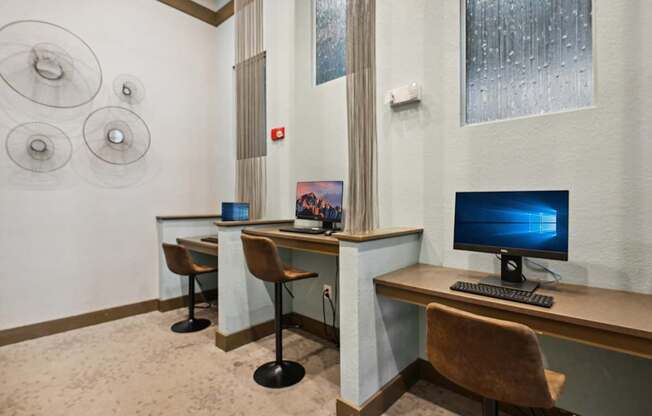 two computer desks with chairs in a room with a computer monitor