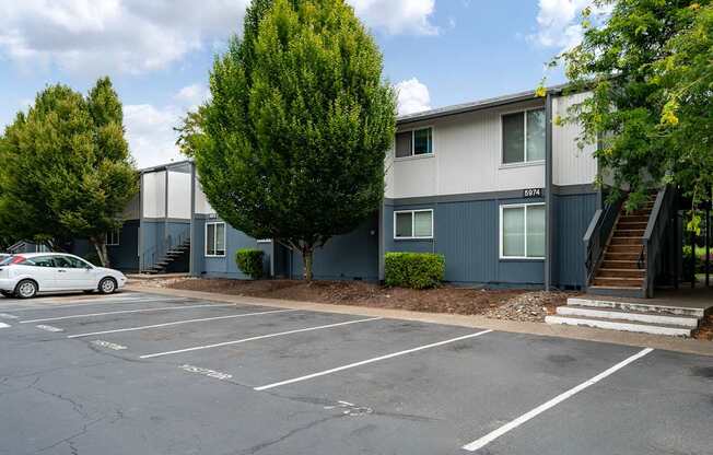 A parking lot with a car parked in front of a building with a grey and blue exterior.