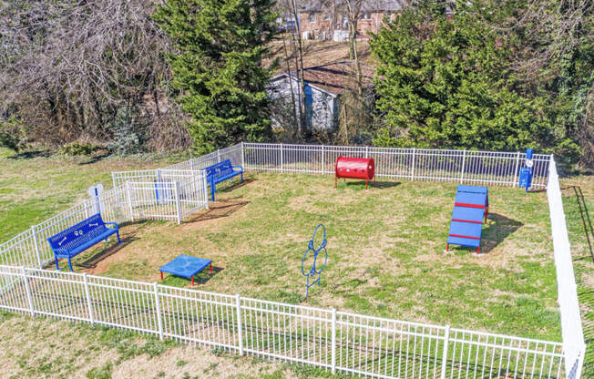 the yard is fenced in and has a play area and a red bench