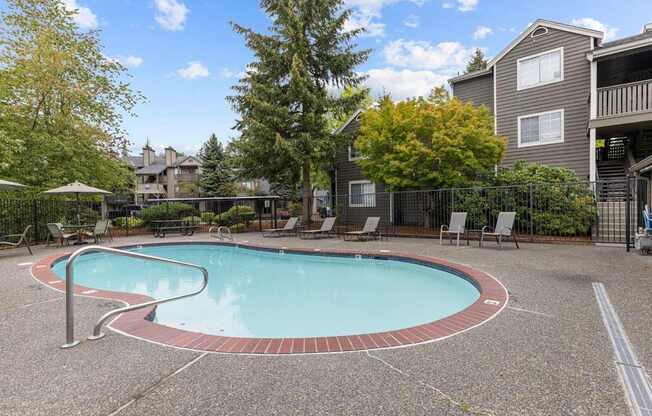 a swimming pool with chairs and a building in the background