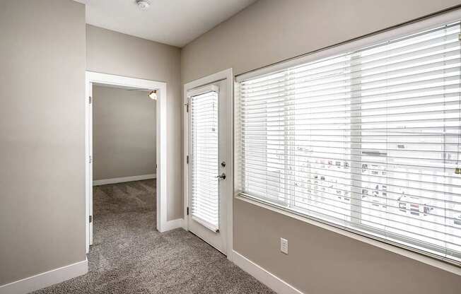 A room with a carpeted floor and a window with blinds.