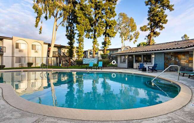 A swimming pool surrounded by trees and apartment buildings.