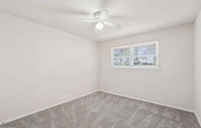 A room with a ceiling fan and a window with a view of a map.