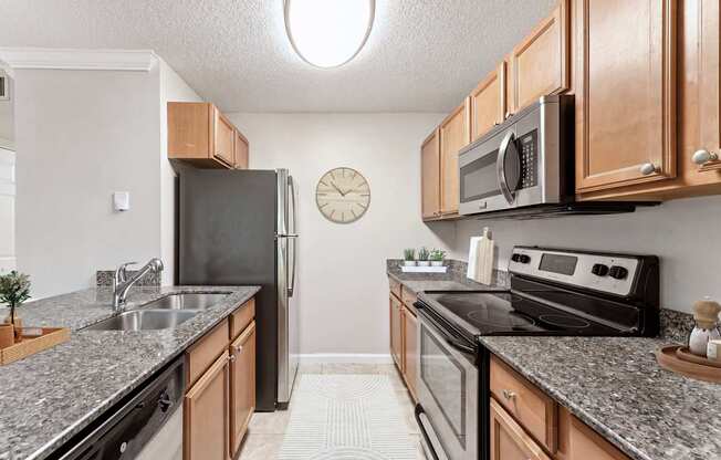 A kitchen with a black refrigerator and stove, wooden cabinets, and a clock on the wall.