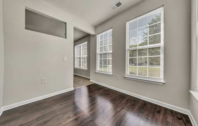 the living room of a new home with wood flooring and large windows