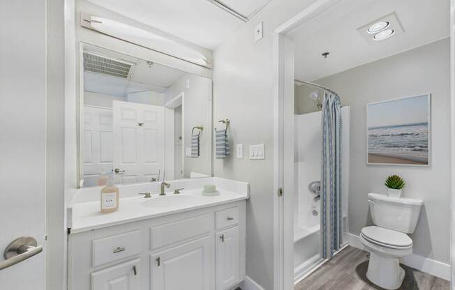A white bathroom with a toilet, sink, and mirror.