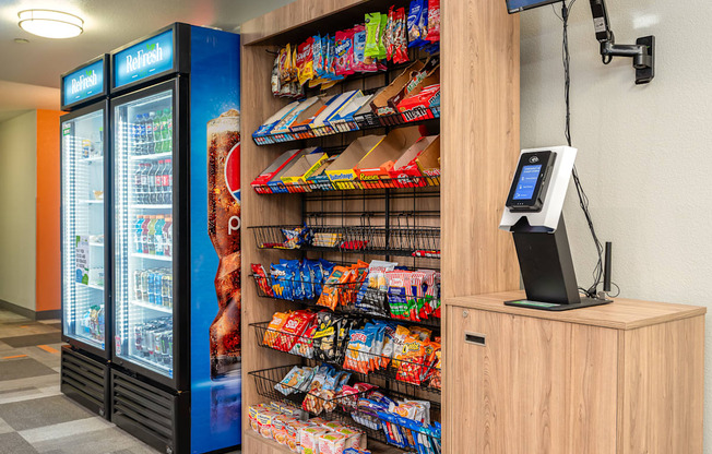 A vending machine selling snacks and drinks is next to a counter with a cash register.