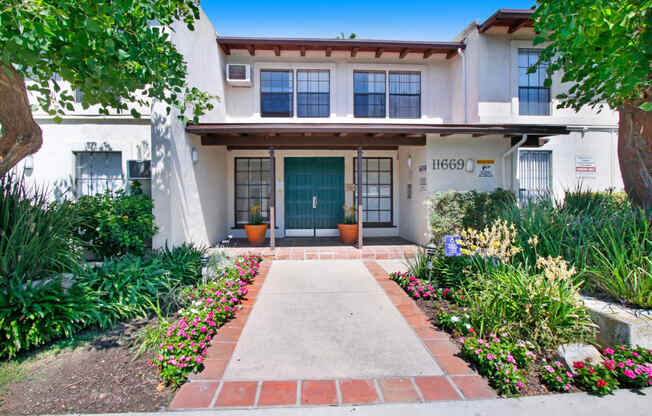 a walkway in front of a white building with a blue door