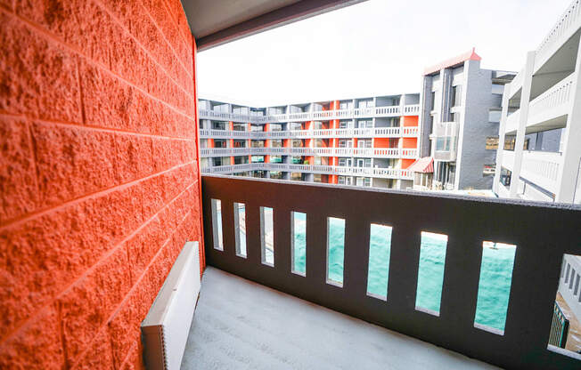 A balcony with a red wall and a view of the sea.