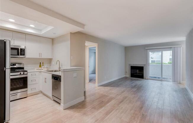 an empty kitchen and living room with a fireplace  at Laguna Gardens Apts., California, 92677