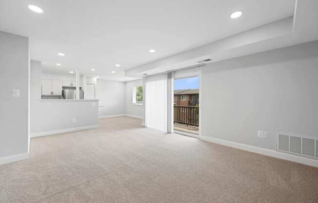 A spacious living room with a sliding glass door leading to a balcony.