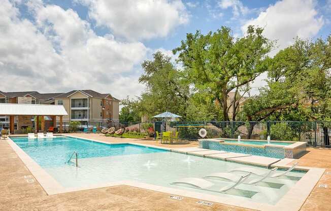 A large outdoor swimming pool with a slide and a fence.