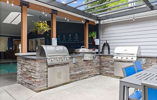 A patio with a stone barbecue and a table.