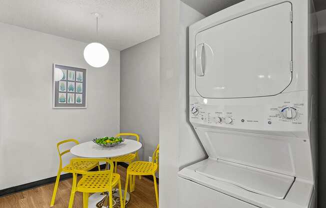 a laundry room with a table and yellow chairs and a washer and dryer