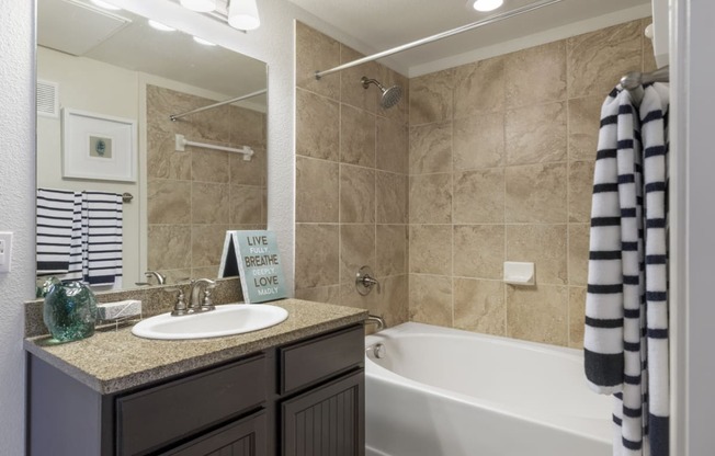 bathroom with granite-style countertops and tile shower surround