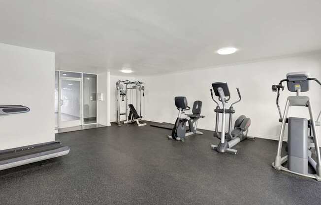 A spacious gym with a variety of equipment including treadmills, stationary bikes, and weight machines.