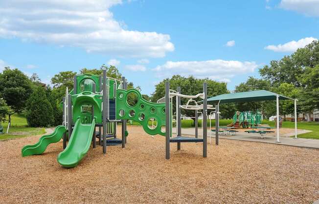 A playground with a green slide and a climbing frame.