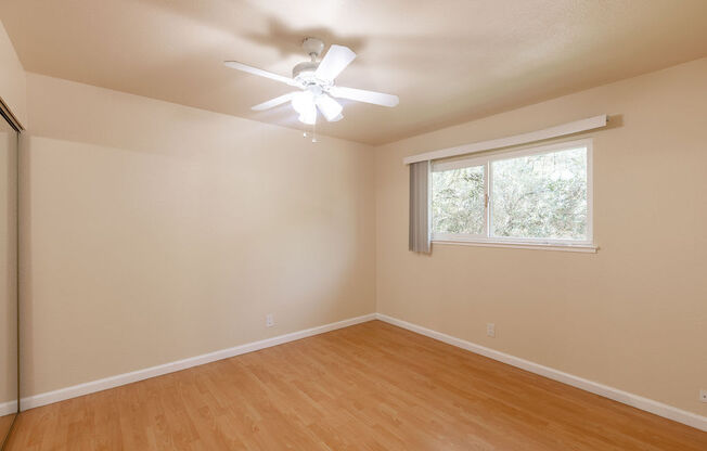 an empty room with a ceiling fan and a window