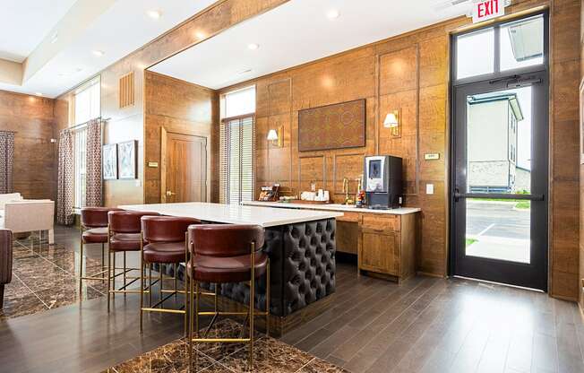 a kitchen with a counter and chairs in a lobby