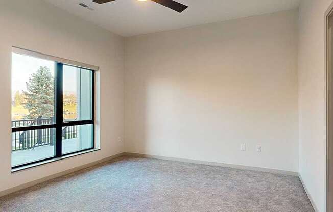a bedroom with a large window and a ceiling fan
