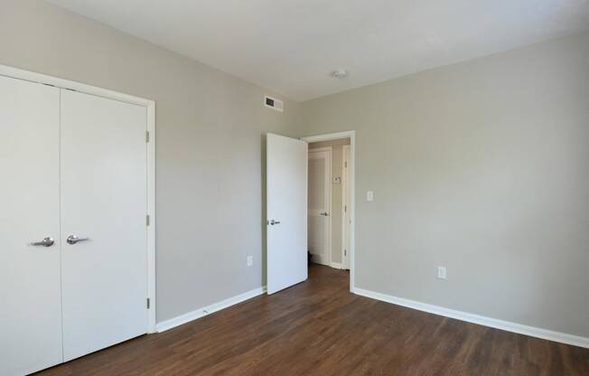 a bedroom with white walls and hardwood floors