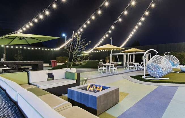a lounge area with couches and a fire pit at night