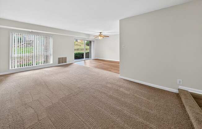 A room with a carpeted floor and a ceiling fan.