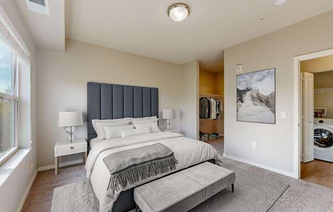 A bedroom with a large bed and a washing machine in the laundry area.