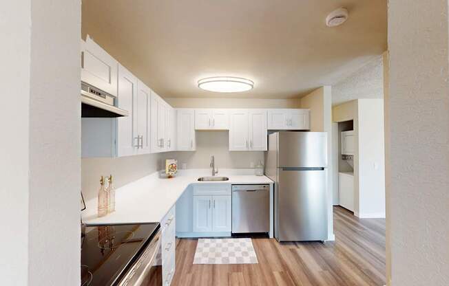 Contemporary kitchen at Peak 88 Apartments Renton WA with sleek white cabinets, stainless appliances, and wood-style floors.