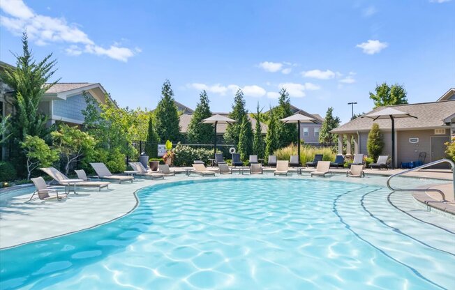 a swimming pool with chaise lounge chairs and umbrellas in front of a row of