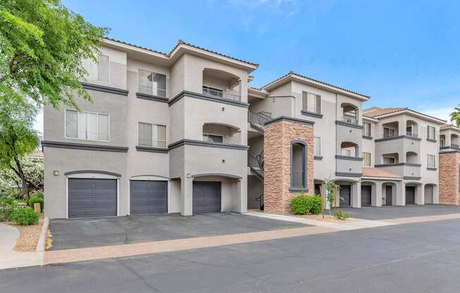 a street view of an apartment building with garage doors