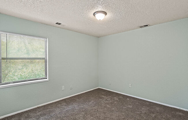 an empty room with a large window and carpet